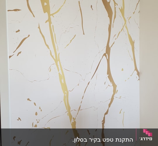 קיר מעוצב המחופה בטפט בדוגמת שיש לבן עם עורקים מוזהבים